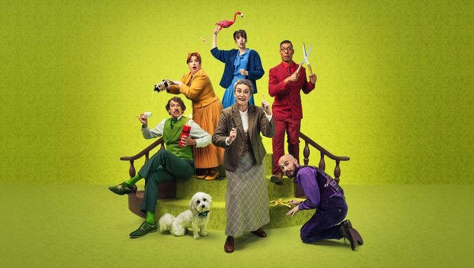 Ensemble cast of Murder, She Didn't Write pose with quirky props and a dog against a bright green backdrop.