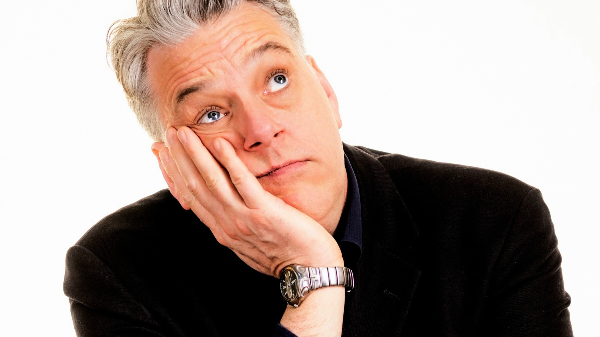 Performer rests head on hand and looks upward against a plain white background